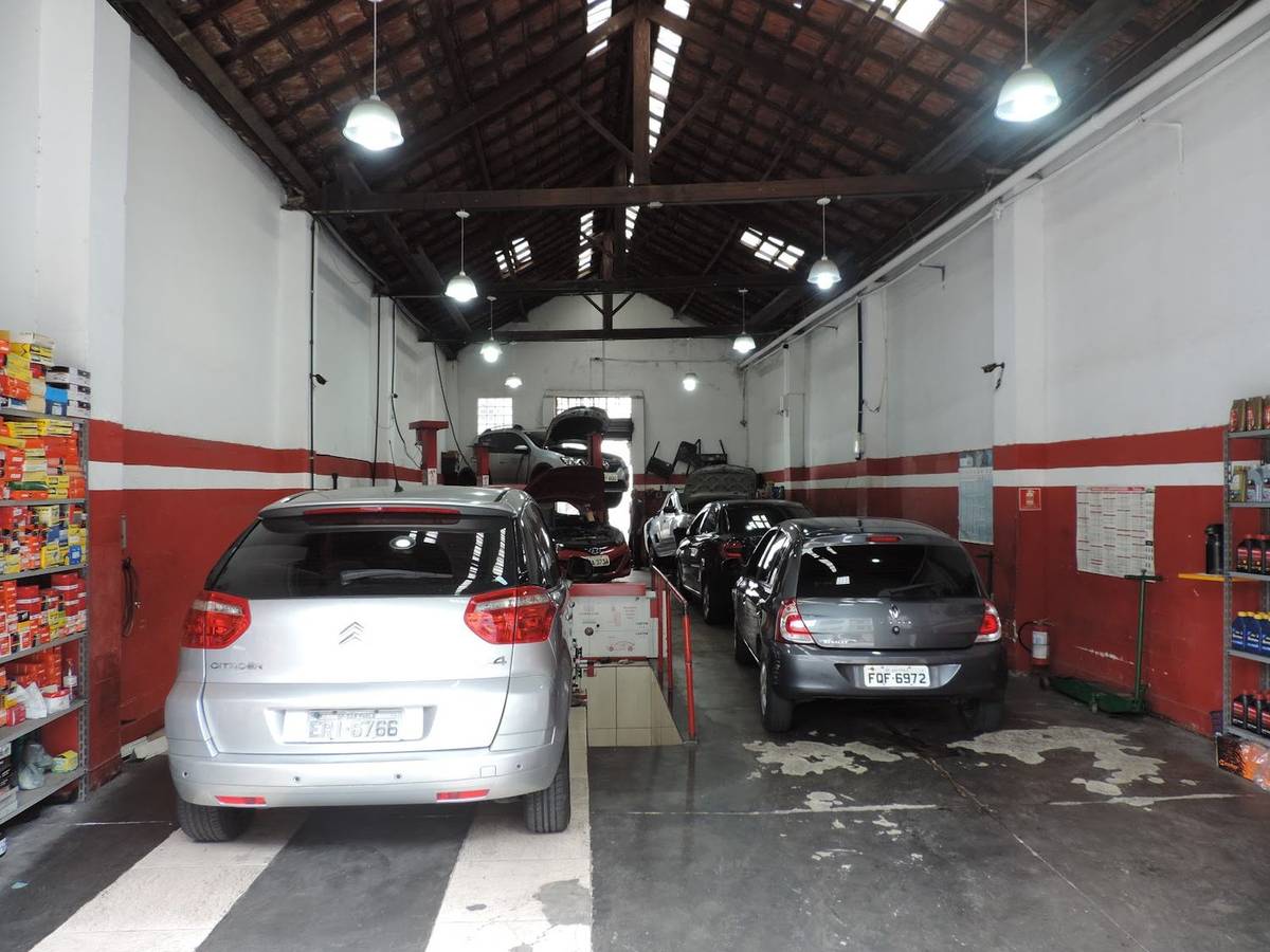Interior estreito do galpão do Giros Auto Center com carros enfileirados em manutenção