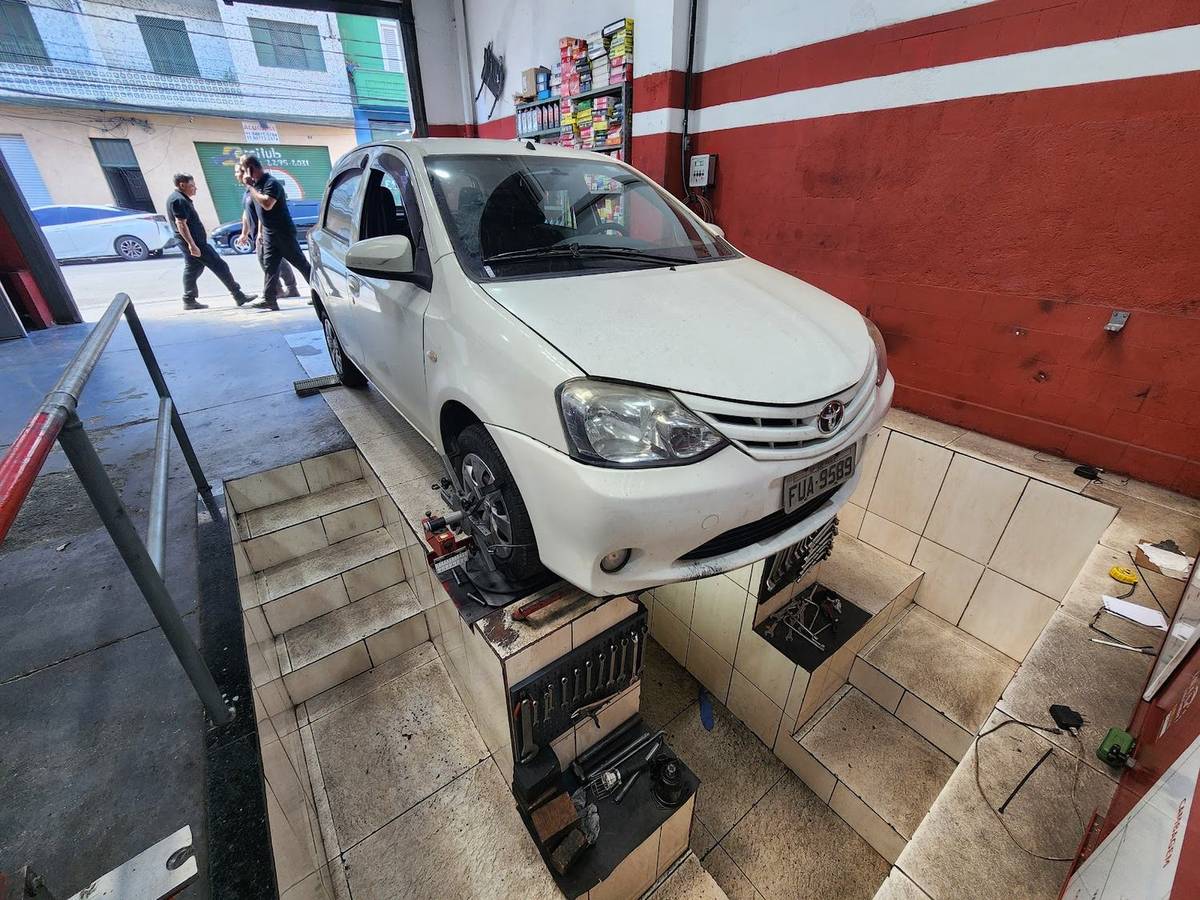 Carro branco sobre a rampa elevada da oficina, visto de cima